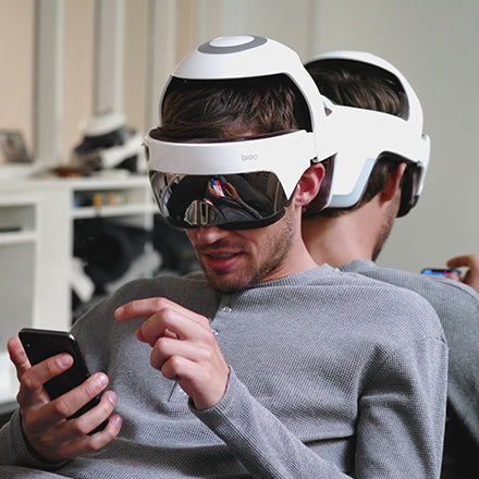 Using a headache head massager while using a mobile phone