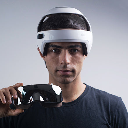 Man wearing a Breo electric head massager and holding an electric eye massager.